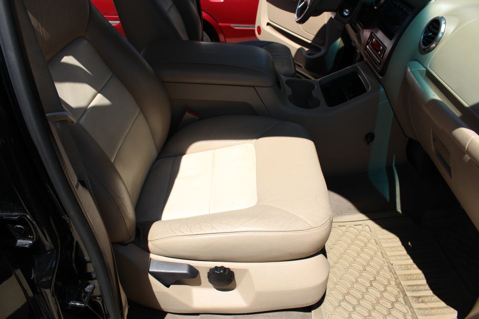 Tan leather seats and dashboard of a vehicle, with a red vehicle visible in the background