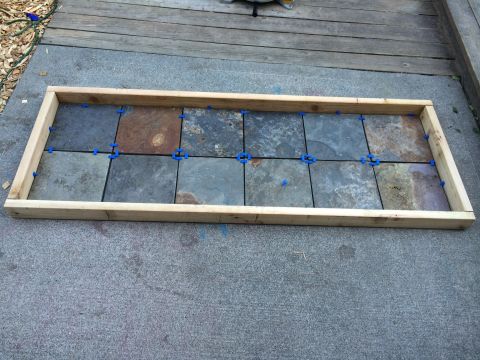 2008 Ford F-250 - Slate tiles are laid out and spaced with blue tile spacers within a wooden frame, ready for grouting.