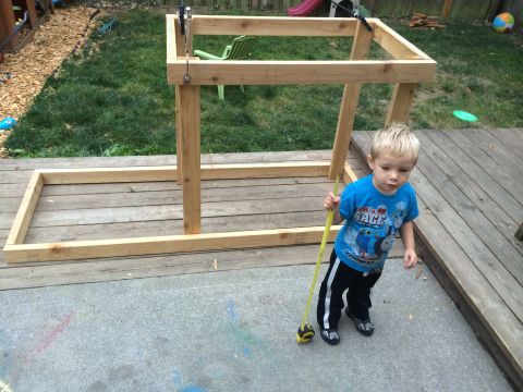 2008 Ford F-250 - A young child stands with a measuring tape near a wooden structure being built in a backyard.
