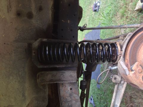 1979 Ford Bronco - Close-up view of a vehicle's suspension system, focusing on the spring and brake components.