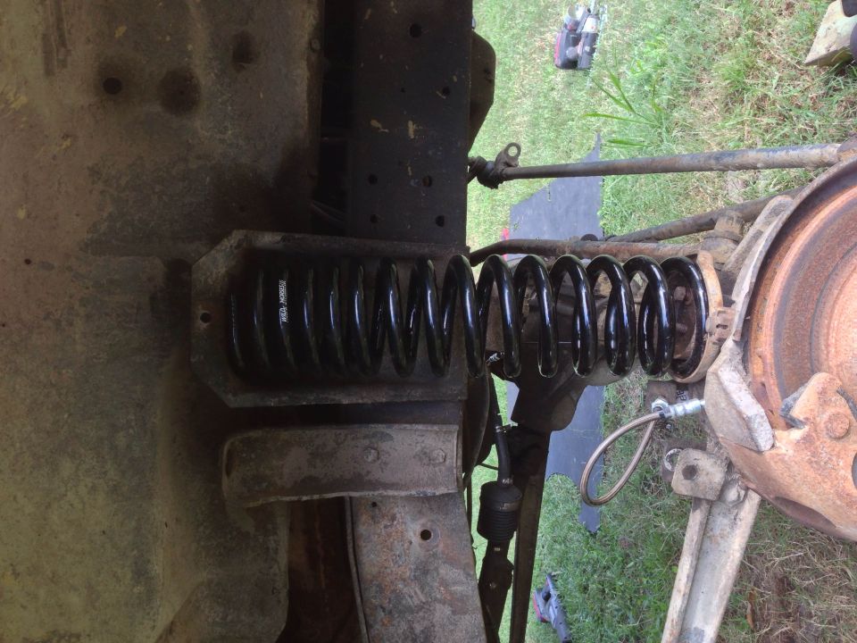 Vehicle suspension spring and brake assembly, showing rust and wear