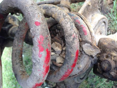 1979 Ford Bronco - This is a close-up view of a rusty coil spring with red paint marks, appearing to be a vehicle part.