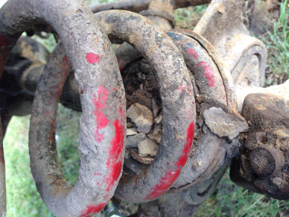 Close-up of a rusty coil spring with red paint marks, likely a vehicle suspension part