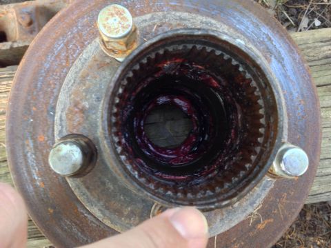 1979 Ford Bronco - Close-up of a rusty wheel hub, showing the splined interior filled with purple grease.