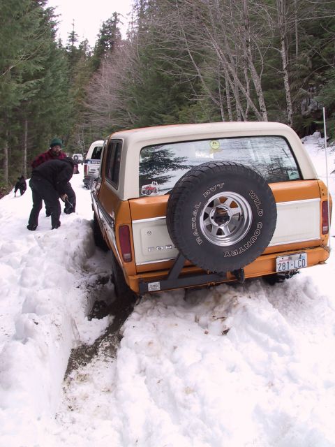 1991 Ford Bronco - Two people attempt to free a Ford Bronco stuck in deep snow on a wooded trail.