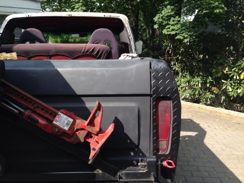1979 Ford Bronco - The rear of a classic Ford Bronco, equipped with racing seats and a Hi-Lift jack, sits outdoors.