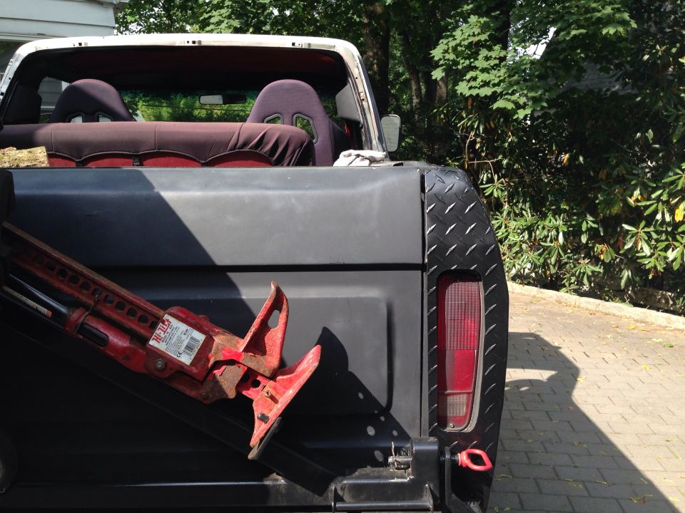 Rear of a 1979 Ford Bronco with racing seats visible inside and a Hi-Lift jack in the bed