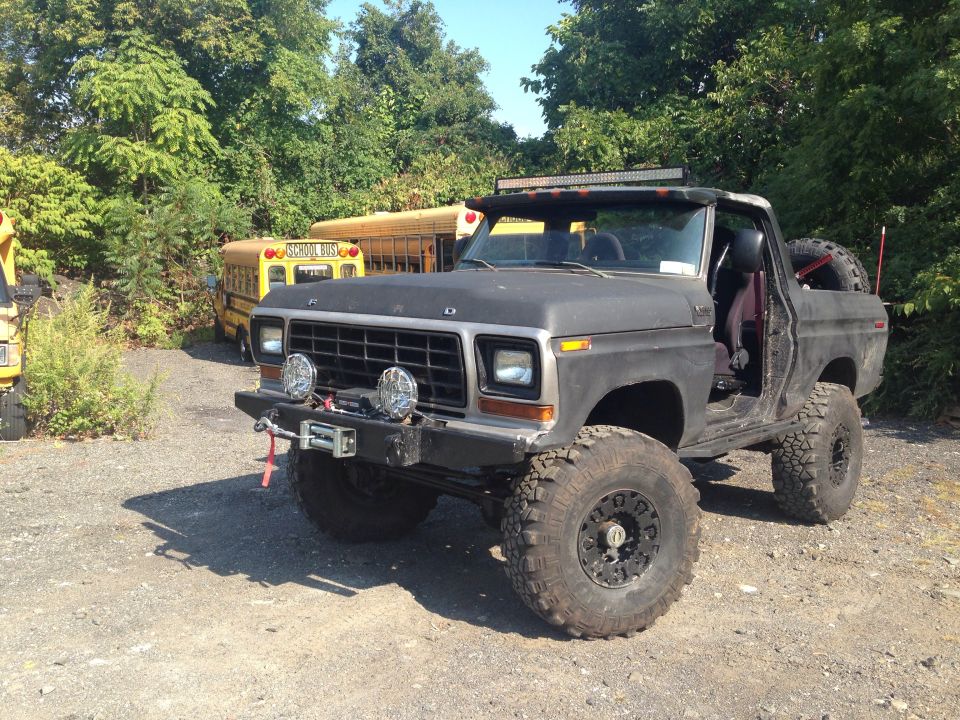 Black Ford Bronco with off-road tires, winch, and light bar, parked outdoors