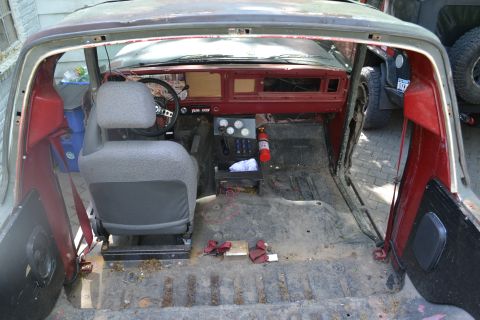 1979 Ford Bronco - The interior of a classic Ford Bronco, seen from the rear, reveals a worn dashboard and seats, with another vehicle visible in the backgrou…