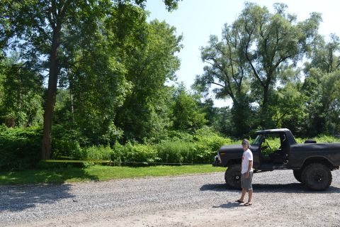 1979 Ford Bronco - A person stands beside a lifted Ford Bronco, its doors removed, in a wooded area.