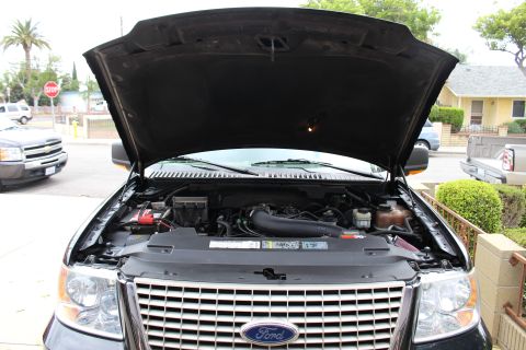 2003 Ford Expedition - The engine bay of a 2003 Ford Expedition is visible with the hood raised, parked in a residential area.