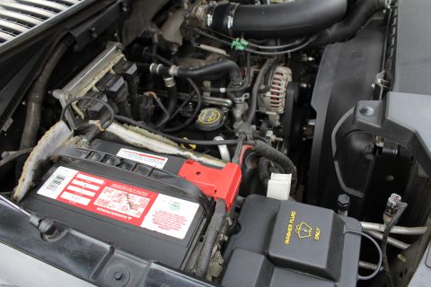 2003 Ford Expedition - Close-up view of a vehicle's engine bay, showing the battery, various hoses, and the alternator.