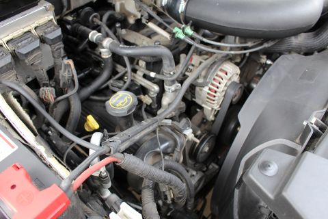 2003 Ford Expedition - Close-up view of a vehicle's engine bay components, including hoses and belts.