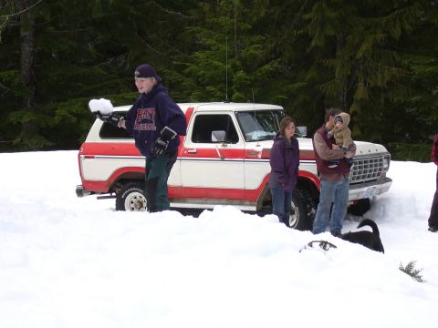 1991 Ford Bronco - A family stands near a white and red Ford Bronco partially buried in snow.