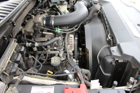 2003 Ford Expedition - The engine bay of a 2003 Ford Expedition is visible, with various components like the alternator and cooling fan clearly depicted.