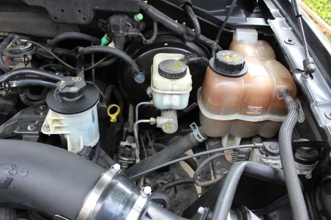 2003 Ford Expedition - Close-up view of the engine bay, showing the power steering fluid reservoir, brake fluid reservoir, and coolant reservoir, along with a K&N…