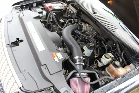 2003 Ford Expedition - Engine bay of a black SUV, an aftermarket K&N air intake system and visible fluid reservoirs.