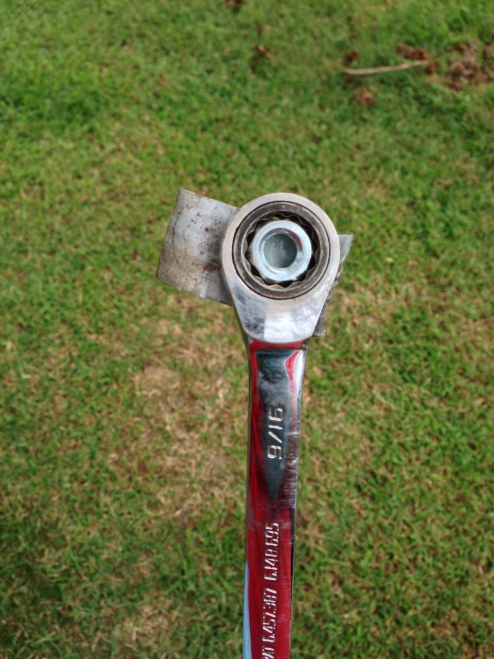 Ratchet wrench with a bearing attached to its head, set against a grassy background