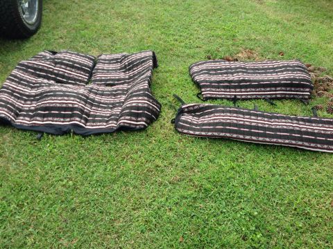 1979 Ford Bronco - Seat covers with a tribal-like stripe pattern are displayed on the grass next to a vehicle.