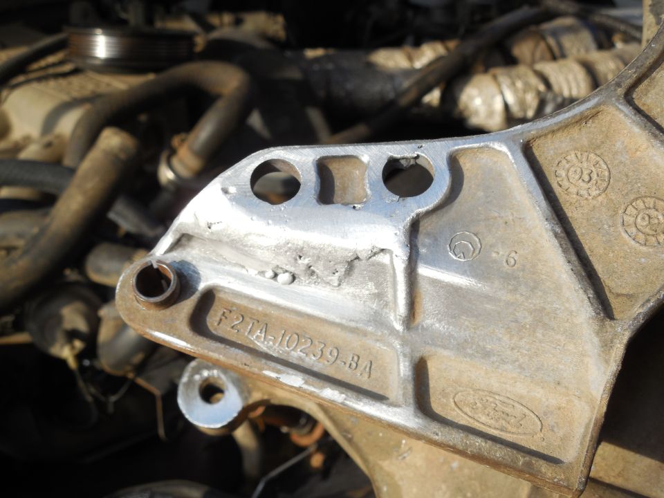 Aluminum Ford bracket marked F2TA-10239-BA on a dusty engine