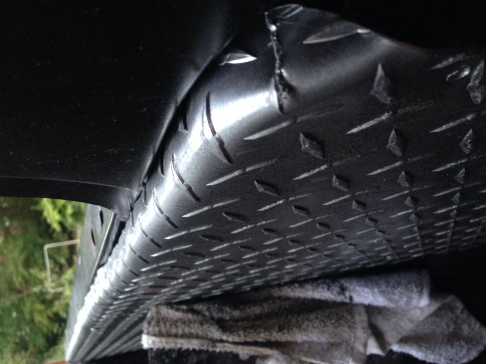 Diamond plate metal under vehicle, part view. Supermotors.net logo visible