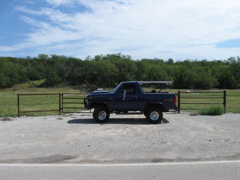1982 Ford Bronco - This 1982 Ford Bronco is parked on a gravel lot next to a fence with trees in the background.