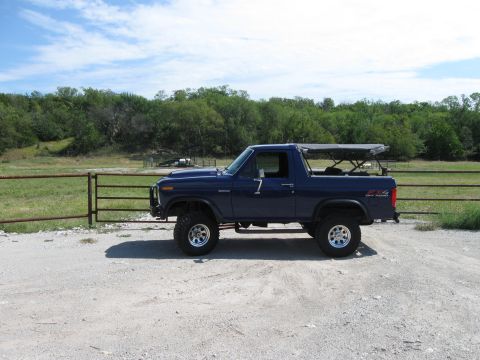 1982 Ford Bronco - Blue Ford Bronco with a soft top and "4x4 OFF ROAD" decal is parked on a gravel lot.