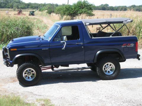 1982 Ford Bronco - Side view of a blue Ford Bronco with a soft top and FX4 Off Road decal.