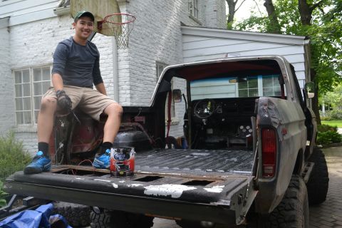 1979 Ford Bronco - A man sits in the open bed of a pickup truck, with the Supermotors logo visible on the tailgate.