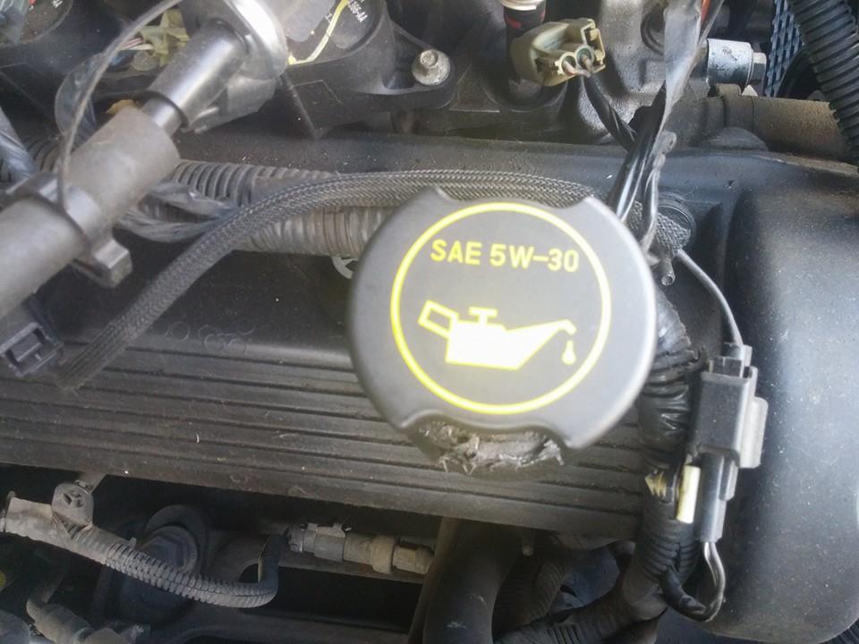 Engine bay detail showing a black oil cap with yellow SAE 5W-30 marking and oil can icon