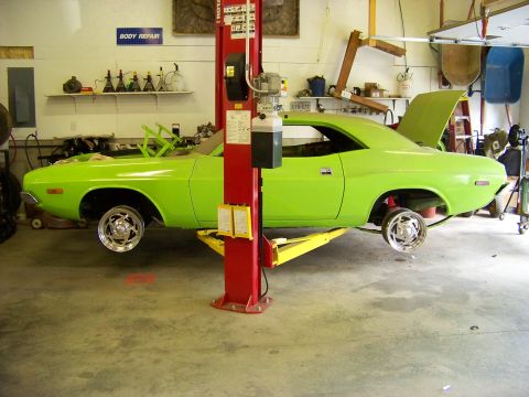1974 Dodge Challenger - A lime green muscle car is being worked on in a garage, with its front wheels removed and hood open.