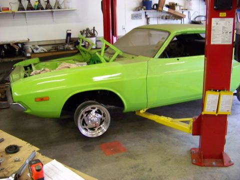 1974 Dodge Challenger - A lime green 1974 Dodge Challenger is shown on a car lift in a garage, with its front wheel off.