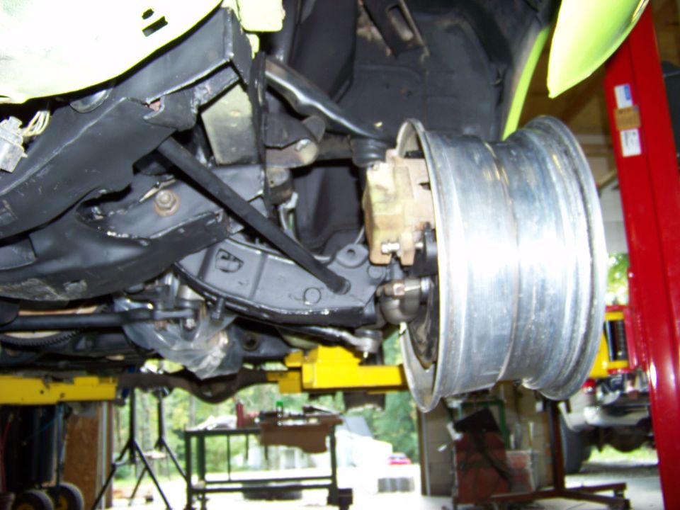 Close-up of vehicle front suspension with a silver wheel attached, viewed from below