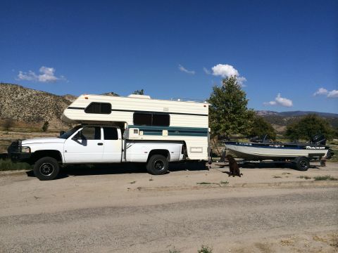 1997 Dodge 3500 - A white 1997 Dodge 3500 dually truck equipped with a camper is seen towing a boat trailer on a sunny day.
