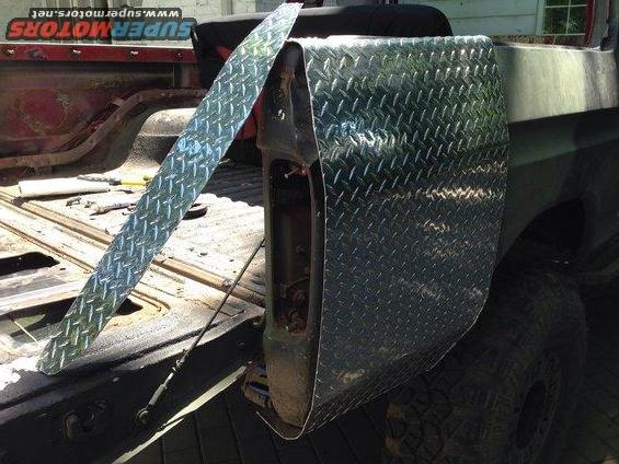 Diamond plate aluminum trim piece laid across the bed of a pickup truck next to the tailgate
