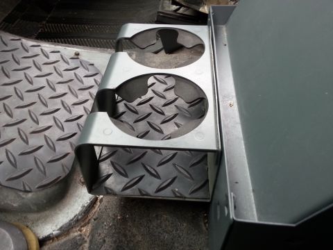 1992 Ford Bronco - A close-up view of a metal cup holder assembly with a diamond plate base, installed inside a vehicle.