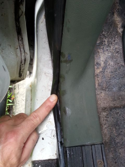 1992 Ford Bronco - A finger points to a gap in the door threshold seal, indicating a potential leak point.