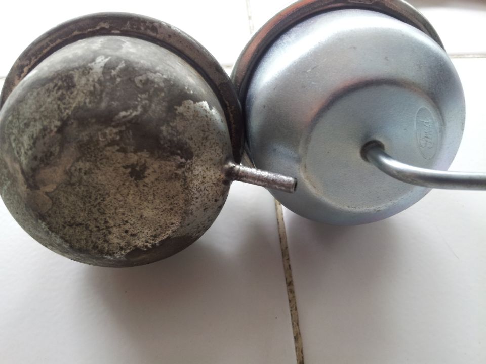 two vacuum actuators, one old and corroded, the other new with a Ford logo