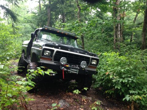 1979 Ford Bronco - A black 1978 Ford Bronco navigates a wooded trail with off-road modifications.
