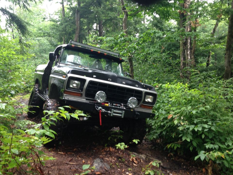 Black 1978 Ford Bronco off-roading with a winch and light bar