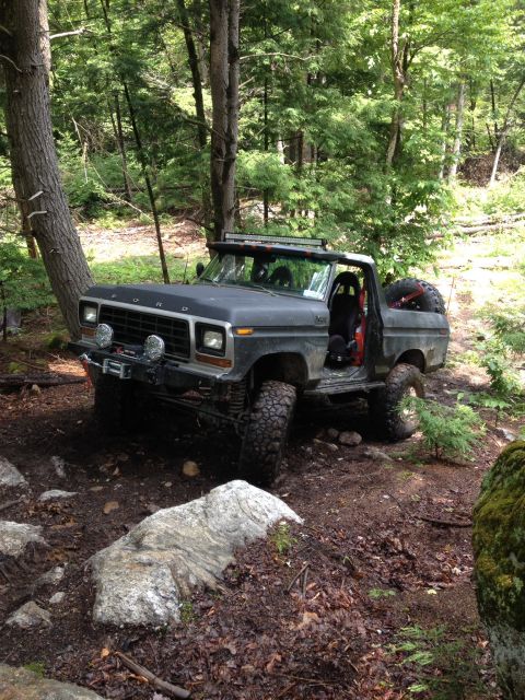 1979 Ford Bronco - Ford Bronco navigates a rocky, wooded path with its doors open.
