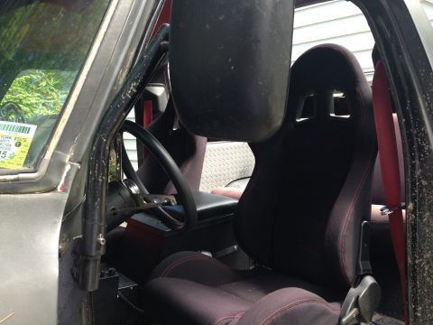 1979 Ford Bronco - The interior of a vehicle shows racing seats and a roll cage, with a New York State inspection sticker visible.