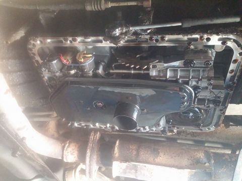 2000 Mercury Grand Marquis - Close-up view of a vehicle's transmission pan and filter assembly, with visible internal components and exhaust pipe.