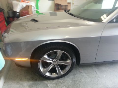 2015 Dodge Challenger - A silver Dodge Challenger is shown from the front quarter angle, highlighting its wheel and fender.