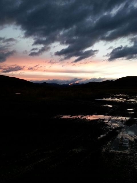 1990 Ford F-250 - A dramatic sunset over a dark, hilly landscape with puddles reflecting the colorful sky.