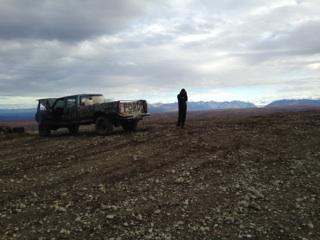 1990 Ford F-250 - A lone figure stands beside a Ford pickup truck in a vast, open terrain under a cloudy sky.