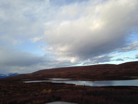 1990 Ford F-250 - A vast landscape unfolds with a tranquil lake reflecting the dramatic sky, bordered by autumnal hills.