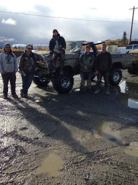 1990 Ford F-250 - A group of men pose with a custom pickup truck in a muddy outdoor setting.