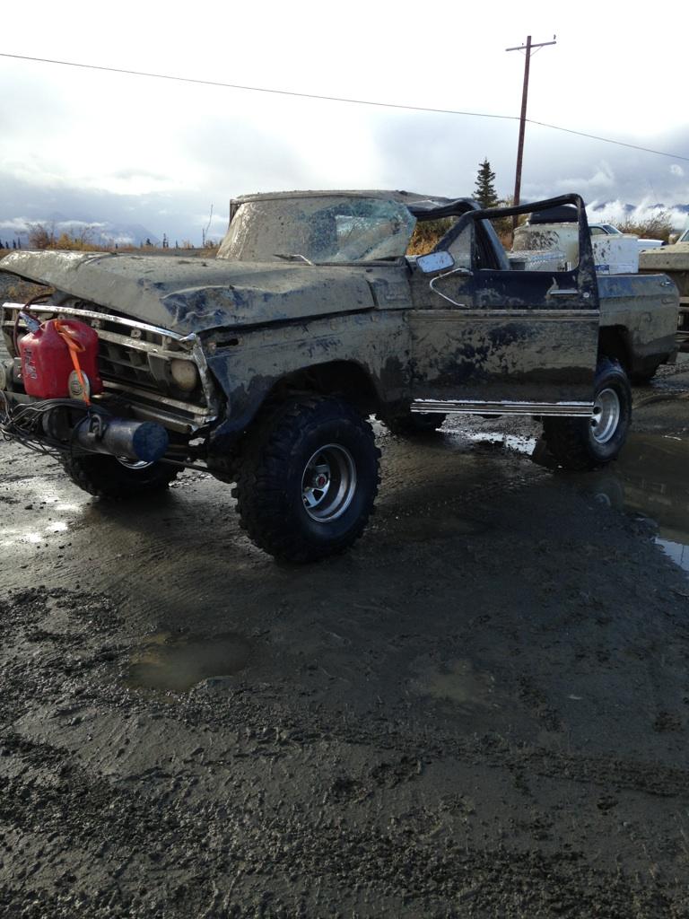 Muddy, damaged truck with a red gas can on the front and a roll bar