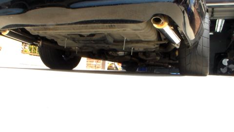 2003 Ford Crown Victoria - Low underside view of a vehicle revealing a polished exhaust tip, muffler and rear suspension components.